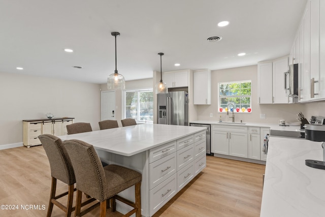 kitchen featuring a kitchen island, appliances with stainless steel finishes, light hardwood / wood-style flooring, and white cabinets