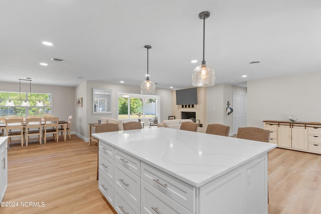 kitchen featuring hanging light fixtures, a brick fireplace, and a healthy amount of sunlight