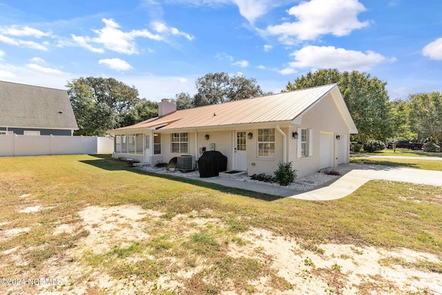 back of house with a garage, a lawn, and central AC unit