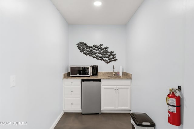 bar featuring white cabinetry, stainless steel appliances, and sink