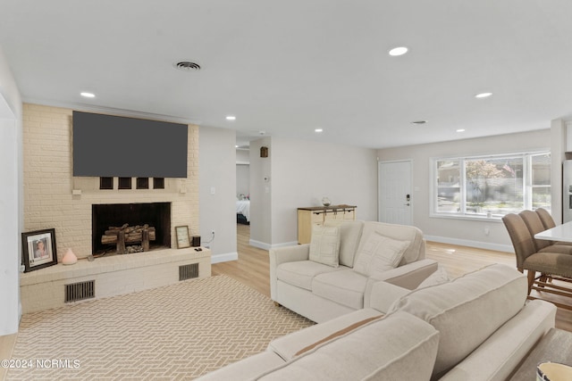 living room featuring light hardwood / wood-style flooring and a brick fireplace