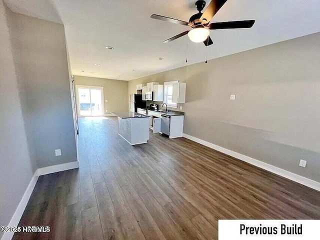 kitchen with dark wood-type flooring, a center island, appliances with stainless steel finishes, ceiling fan, and white cabinets