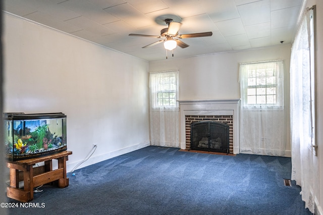 living room with ceiling fan, a healthy amount of sunlight, a brick fireplace, and dark carpet