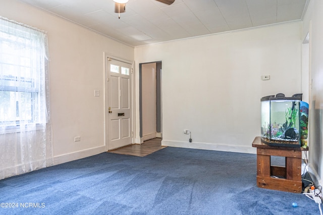 carpeted entrance foyer with ceiling fan and ornamental molding