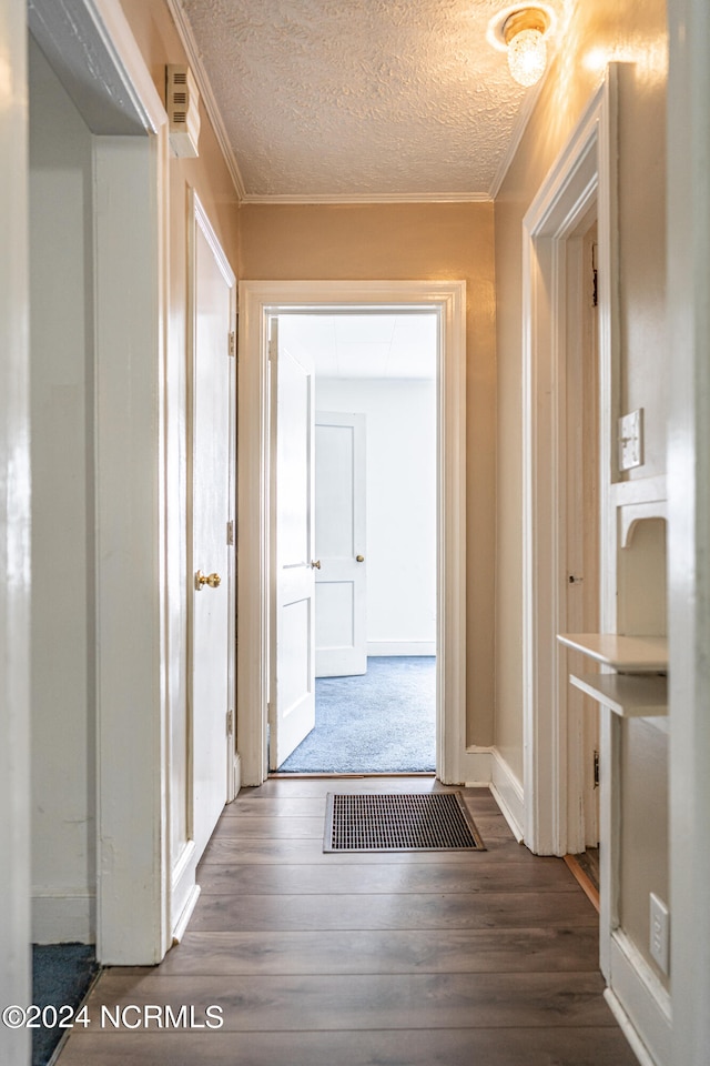 corridor with crown molding, a textured ceiling, and dark hardwood / wood-style flooring