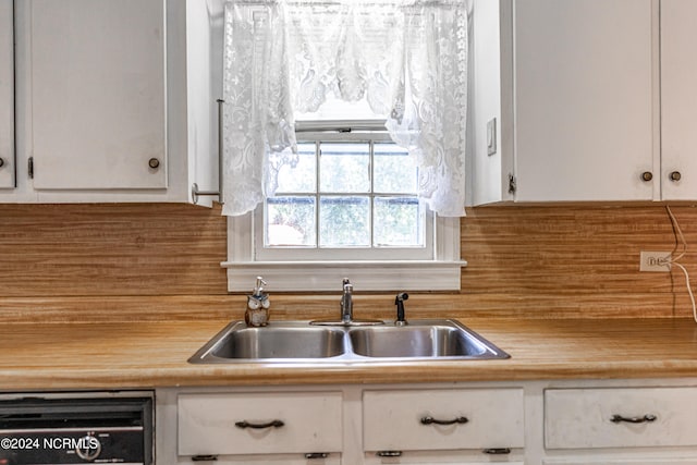 kitchen featuring backsplash, dishwasher, sink, and white cabinets