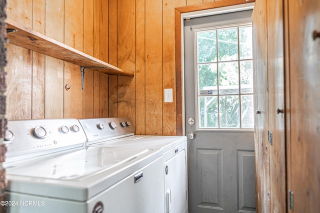 laundry room featuring washing machine and clothes dryer and wood walls