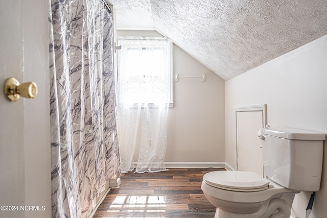 bathroom featuring wood-type flooring, a textured ceiling, toilet, walk in shower, and lofted ceiling