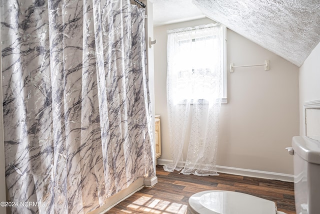 bathroom with toilet, lofted ceiling, a textured ceiling, and wood-type flooring