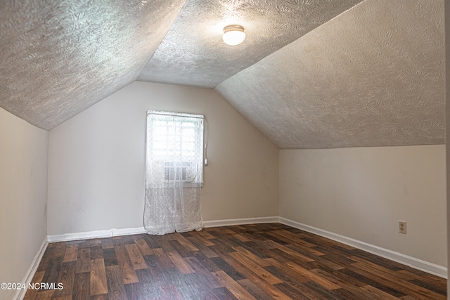 additional living space featuring lofted ceiling, a textured ceiling, and dark hardwood / wood-style flooring