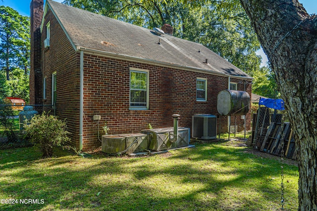 rear view of property with cooling unit and a lawn