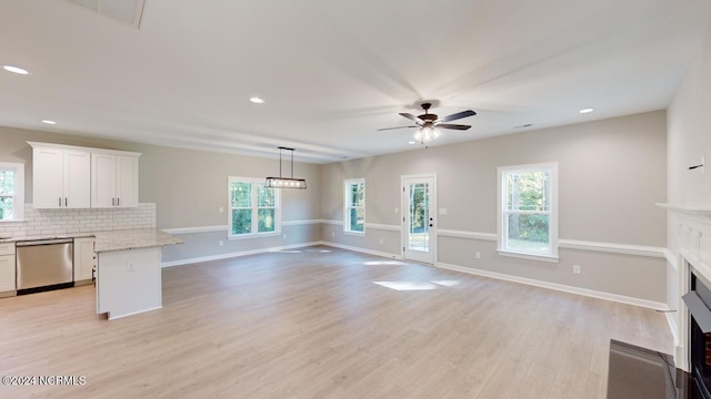 unfurnished living room with light wood-type flooring, plenty of natural light, and ceiling fan