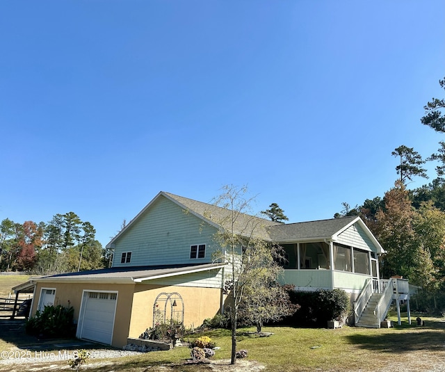 view of front facade featuring a garage, a sunroom, and a front yard