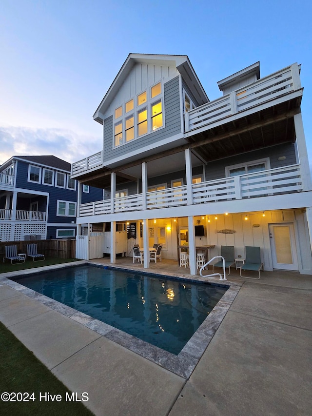 rear view of property with a balcony, a fenced in pool, and a patio