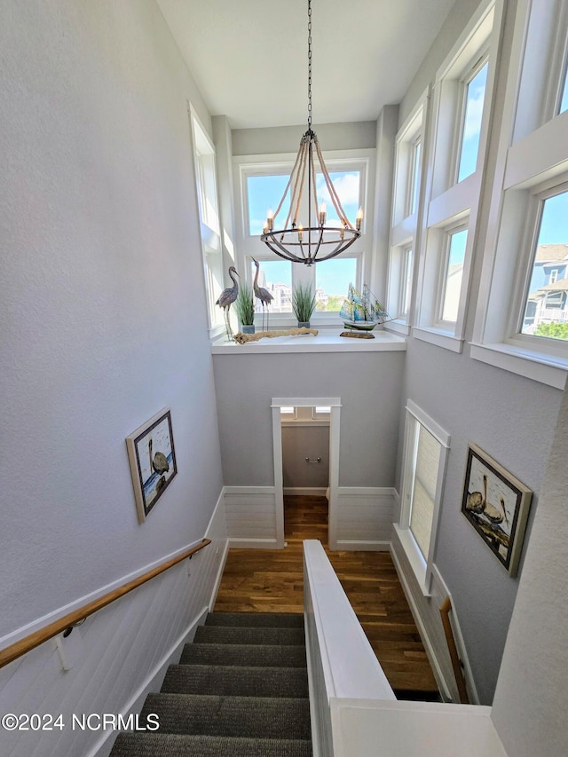 staircase featuring hardwood / wood-style flooring, a wealth of natural light, and a notable chandelier