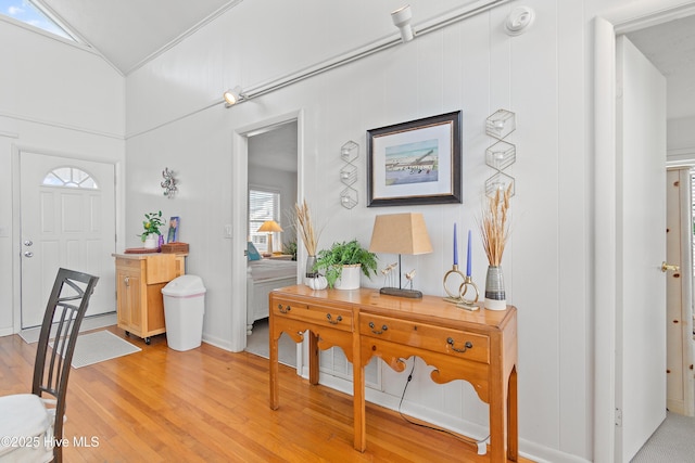 entryway featuring vaulted ceiling, plenty of natural light, ornamental molding, and light wood-type flooring