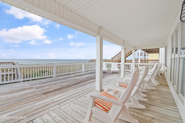 wooden deck with a water view and a view of the beach