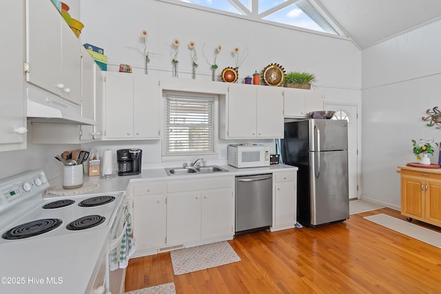 kitchen with sink, light hardwood / wood-style flooring, white cabinetry, stainless steel appliances, and vaulted ceiling