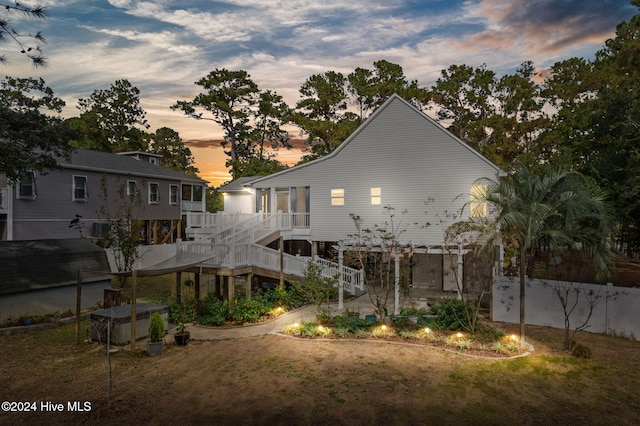 back of house at dusk featuring fence and a lawn