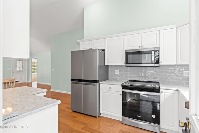 kitchen featuring stainless steel appliances, white cabinetry, light wood-style floors, and decorative backsplash