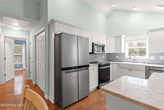 kitchen with stainless steel appliances, backsplash, light wood-style flooring, white cabinets, and a sink