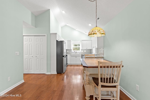 dining space featuring high vaulted ceiling, light wood-type flooring, and baseboards