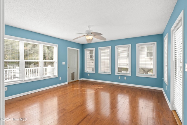 unfurnished room with a textured ceiling, dark wood finished floors, a ceiling fan, and baseboards