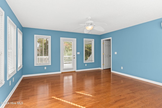 unfurnished room with a ceiling fan, baseboards, and dark wood-type flooring