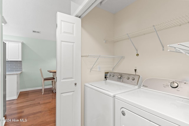 washroom with visible vents, washing machine and dryer, wood finished floors, laundry area, and baseboards