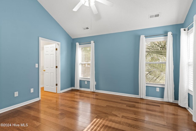 unfurnished room featuring vaulted ceiling, hardwood / wood-style floors, visible vents, and baseboards