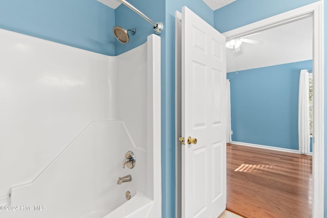 bathroom featuring shower / bath combination, baseboards, and wood finished floors