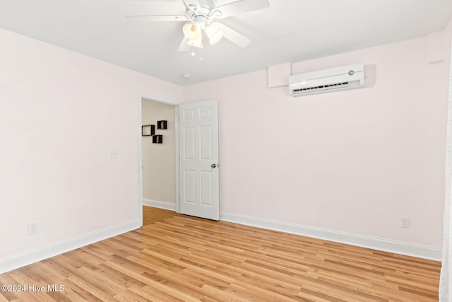 unfurnished room with ceiling fan, light wood-type flooring, a wall mounted air conditioner, and baseboards