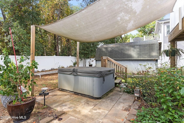 view of patio featuring an outdoor structure, a fenced backyard, and a hot tub