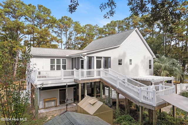 back of property featuring a sunroom, roof with shingles, a wooden deck, and stairs