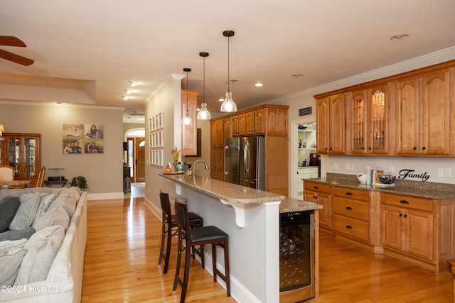 kitchen featuring stainless steel fridge, a breakfast bar, pendant lighting, light wood-type flooring, and beverage cooler