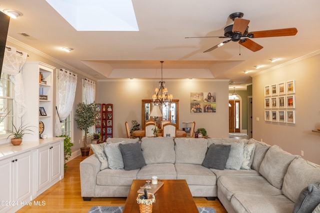 living room featuring light hardwood / wood-style flooring, crown molding, and a tray ceiling