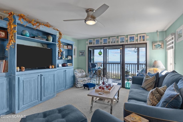 living room with a water view, ceiling fan, and light colored carpet