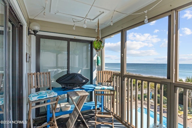 sunroom / solarium featuring a water view and a view of the beach