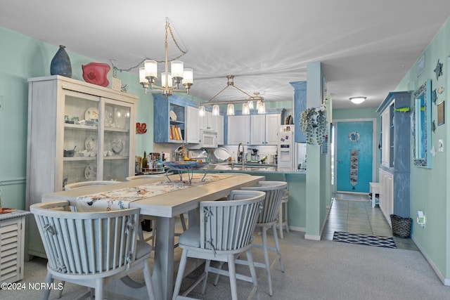 kitchen with kitchen peninsula, sink, pendant lighting, white cabinets, and white appliances