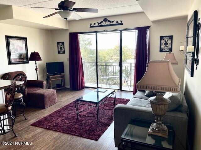 living room featuring ceiling fan, a textured ceiling, and hardwood / wood-style flooring