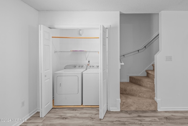 laundry room featuring washing machine and clothes dryer and light hardwood / wood-style floors