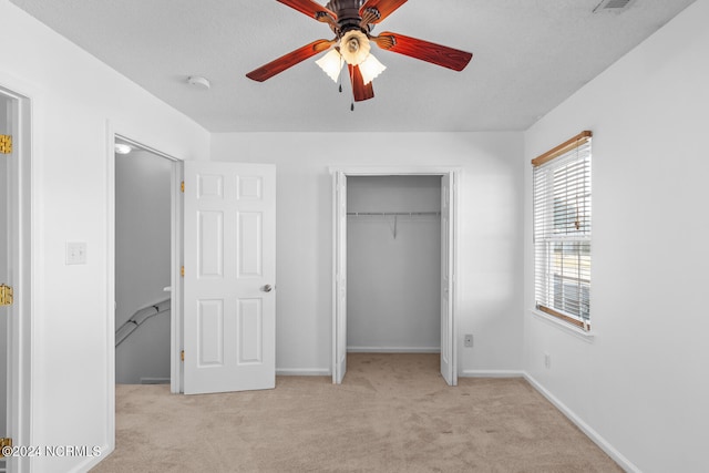 unfurnished bedroom featuring ceiling fan, light carpet, and a textured ceiling