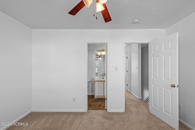 unfurnished bedroom with light carpet, a textured ceiling, ensuite bath, and ceiling fan