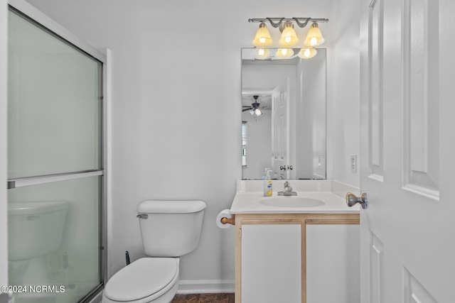 bathroom with toilet, a shower with shower door, vanity, and ceiling fan