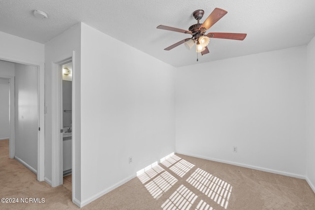 empty room with light carpet, a textured ceiling, and ceiling fan