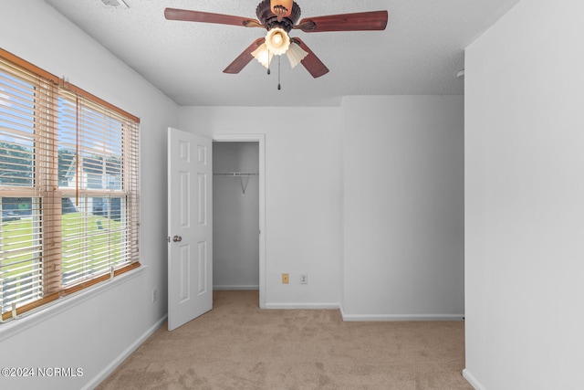 unfurnished bedroom featuring a closet, a textured ceiling, light colored carpet, and ceiling fan