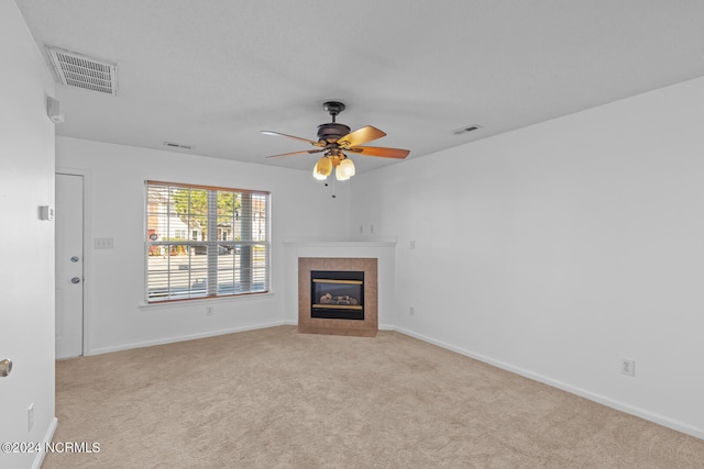 unfurnished living room with light carpet, a tile fireplace, and ceiling fan