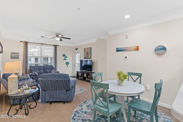 carpeted dining area featuring crown molding and ceiling fan