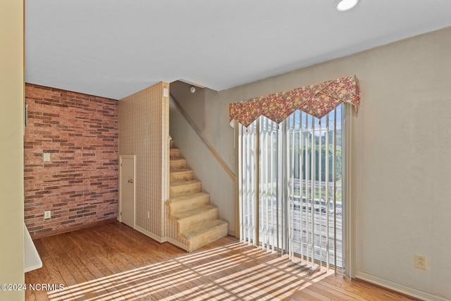 stairway with brick wall and hardwood / wood-style floors