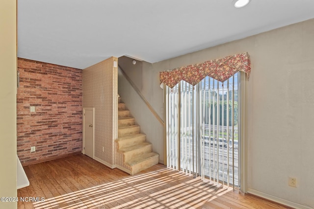 124 N Lisk Dr, Swansboro, NC 28584 - unfurnished room featuring wood finished floors, brick wall, and stairway